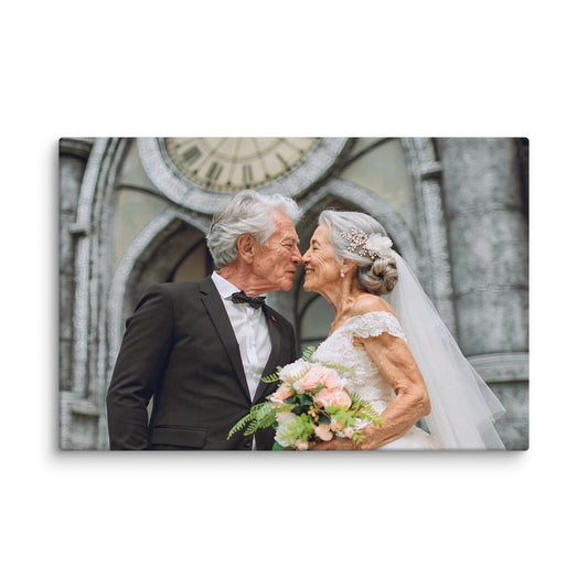 Couple in wedding attire kissing in front of a cathedral clock tower.
